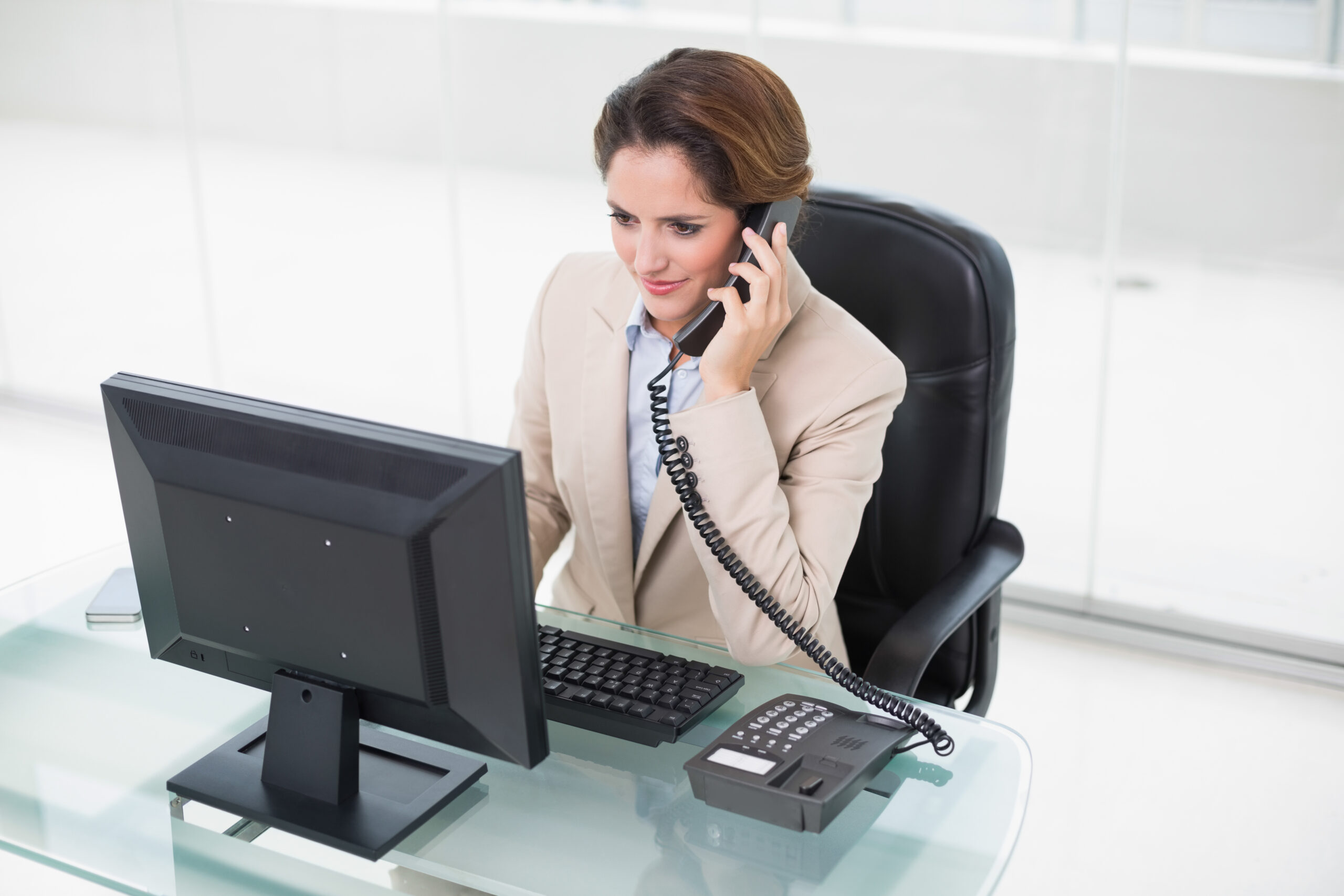 brunette-businesswoman-using-phone-looking-computer